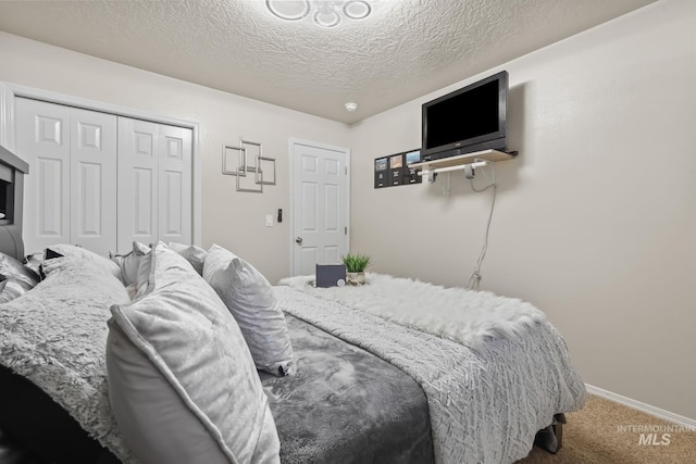 bedroom with a closet, a textured ceiling, baseboards, and carpet floors