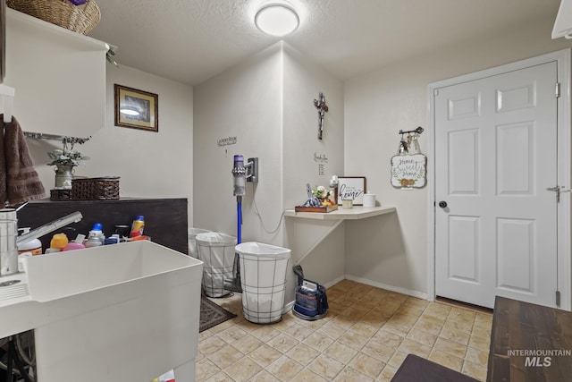 bathroom with a textured ceiling, baseboards, and a sink