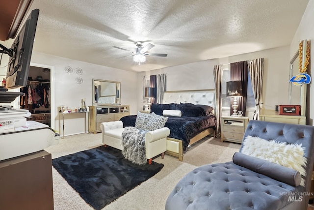 bedroom with ceiling fan, carpet flooring, and a textured ceiling