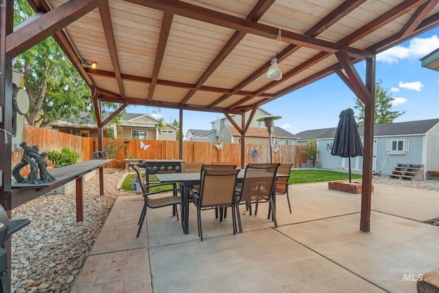 view of patio / terrace featuring a fenced backyard, outdoor dining space, a storage shed, and an outdoor structure