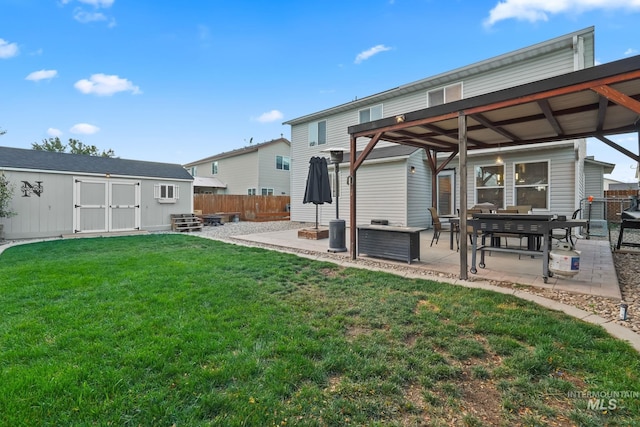 rear view of house with an outdoor structure, a lawn, fence, and a patio area