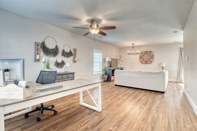 living room with ceiling fan with notable chandelier, a textured ceiling, and light hardwood / wood-style floors