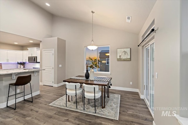 dining room featuring high vaulted ceiling and dark wood-type flooring