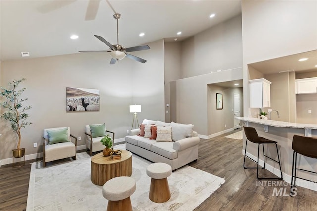 living room with high vaulted ceiling, ceiling fan, and dark wood-type flooring