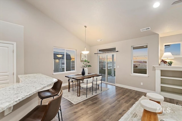 dining room with vaulted ceiling and dark wood-type flooring