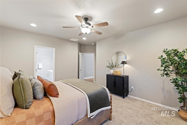 bedroom with ceiling fan, light colored carpet, and ensuite bath