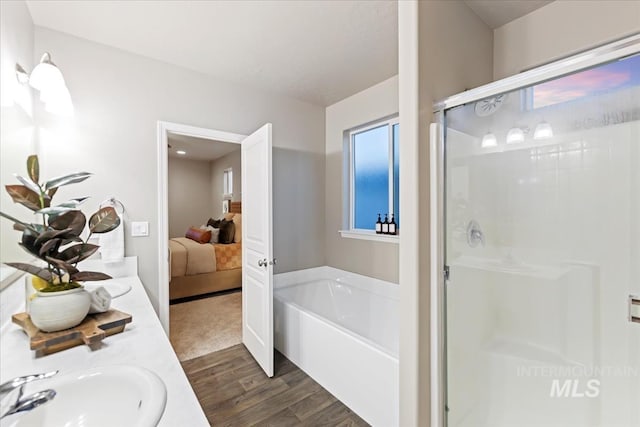 bathroom featuring plus walk in shower, vanity, hardwood / wood-style flooring, and a healthy amount of sunlight