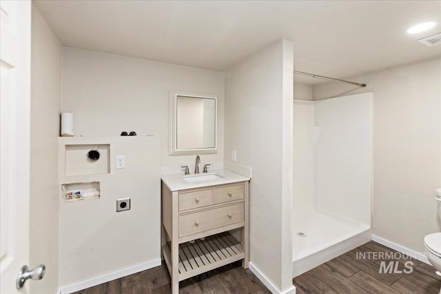 bathroom with a shower, hardwood / wood-style floors, vanity, and toilet