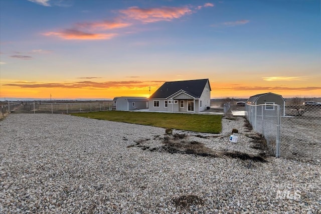 back house at dusk featuring a lawn