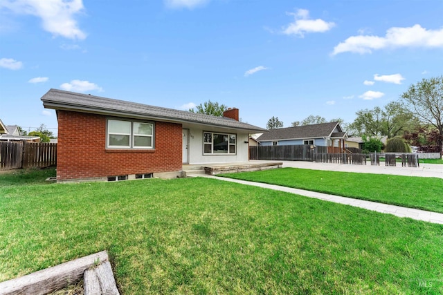 view of front of home featuring brick siding, fence, a chimney, and a front lawn