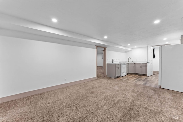 finished below grade area featuring light colored carpet, freestanding refrigerator, a sink, and recessed lighting