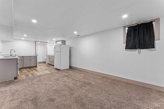 interior space with light colored carpet, a sink, light wood-style flooring, recessed lighting, and baseboards