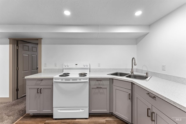 kitchen featuring white electric range oven, dark wood-style floors, light countertops, gray cabinets, and a sink