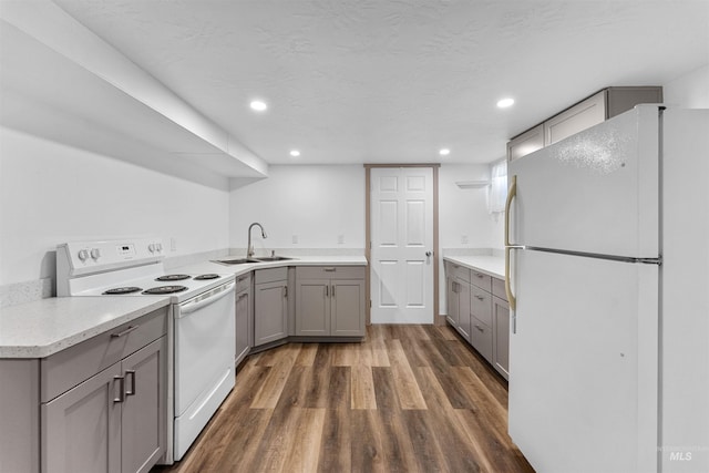 kitchen with gray cabinetry, a sink, dark wood-style floors, recessed lighting, and white appliances