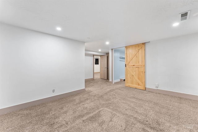 finished basement with baseboards, visible vents, recessed lighting, and light colored carpet