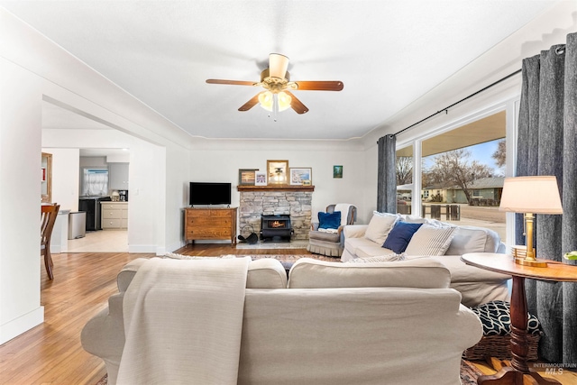 living room with ceiling fan, baseboards, and light wood finished floors