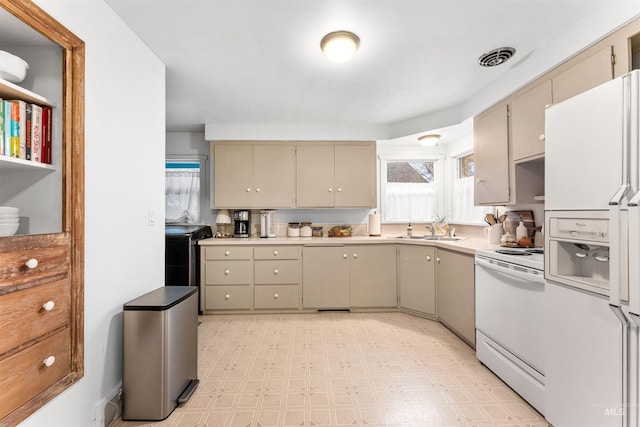 kitchen with electric range, a sink, light countertops, white fridge with ice dispenser, and light floors