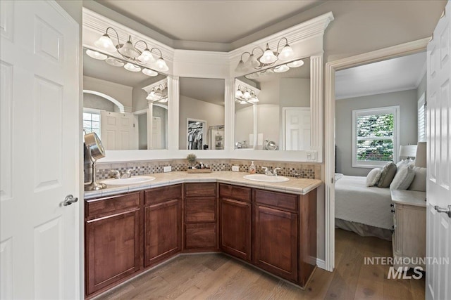 bathroom featuring decorative backsplash, wood-type flooring, vanity, and ornamental molding