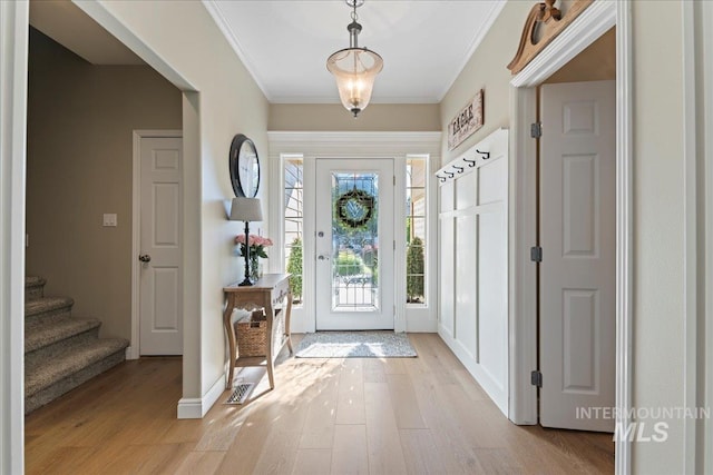 entryway with light hardwood / wood-style flooring and crown molding