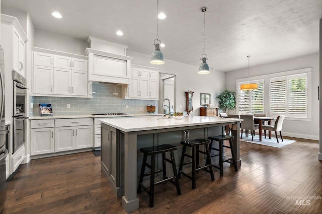 6922 N Agrarian, Meridian, ID 83646 - kitchen featuring light countertops, a sink, decorative backsplash, white cabinetry, and a kitchen bar