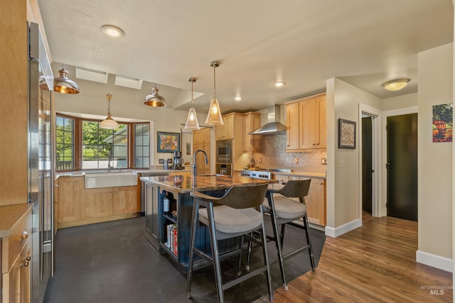 kitchen with dark hardwood / wood-style flooring, light brown cabinetry, a kitchen island with sink, sink, and wall chimney range hood