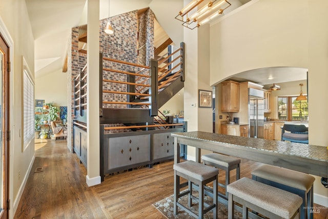 kitchen featuring a high ceiling, a notable chandelier, hardwood / wood-style floors, and stainless steel built in refrigerator