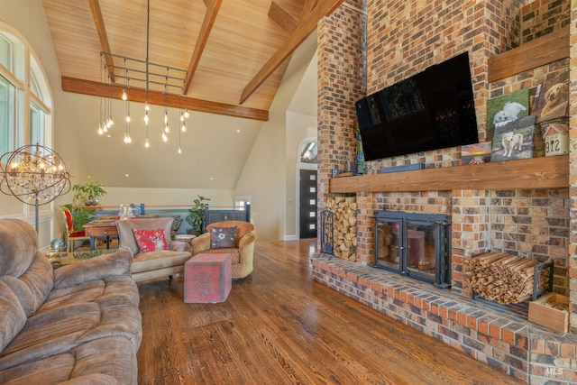 living room featuring dark wood-type flooring, high vaulted ceiling, a notable chandelier, and a brick fireplace