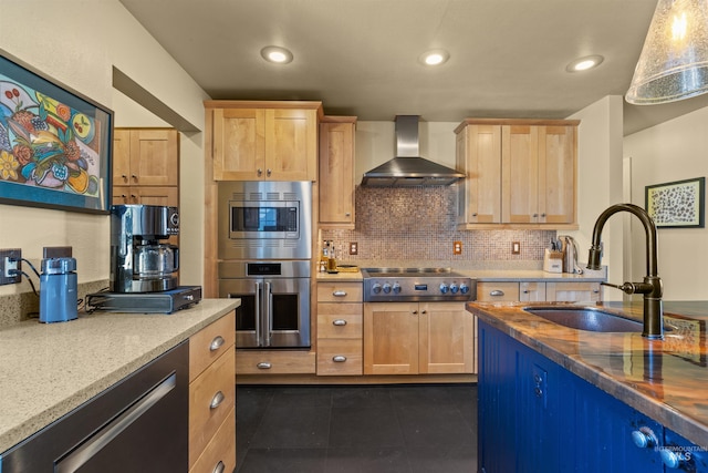 kitchen with tasteful backsplash, stainless steel appliances, dark tile patterned floors, sink, and wall chimney range hood