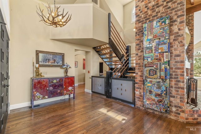 entryway with a high ceiling, dark hardwood / wood-style floors, and a chandelier