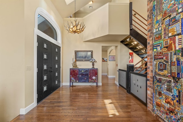 foyer entrance featuring hardwood / wood-style flooring, an inviting chandelier, and a high ceiling