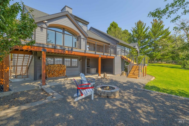 exterior space featuring a fire pit, a wooden deck, a yard, and a patio area