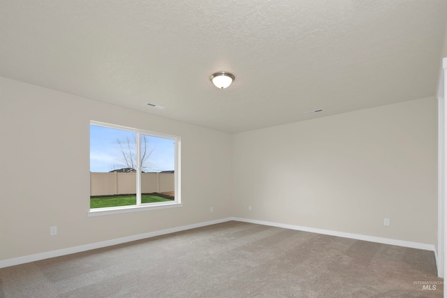 spare room with a textured ceiling and light colored carpet