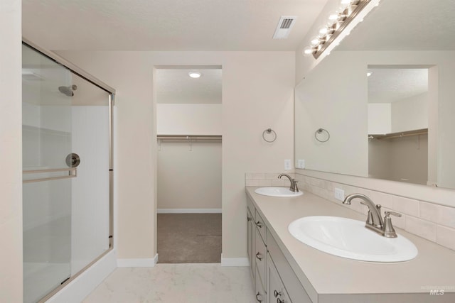 bathroom with an enclosed shower, vanity, and a textured ceiling