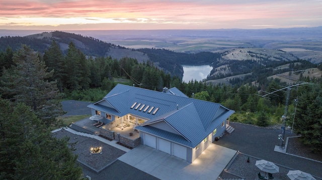 aerial view at dusk featuring a forest view and a mountain view