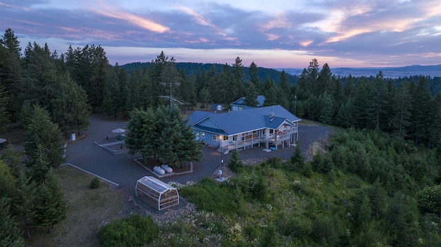 aerial view at dusk featuring a forest view