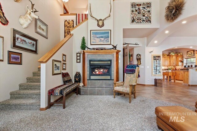 living room featuring arched walkways, stairs, recessed lighting, a tile fireplace, and baseboards