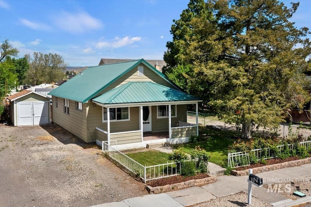 68 W Garfield Ave, Glenns Ferry, ID 83623 - view of front of home with a porch, a storage unit, gravel driveway, an outdoor structure, and metal roof