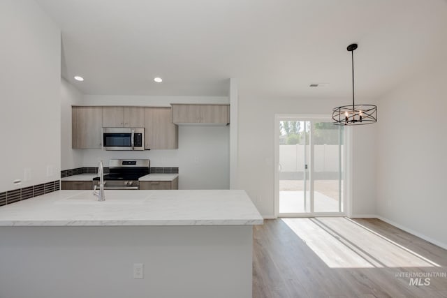 kitchen featuring light wood-type flooring, light brown cabinets, stainless steel appliances, decorative light fixtures, and a chandelier