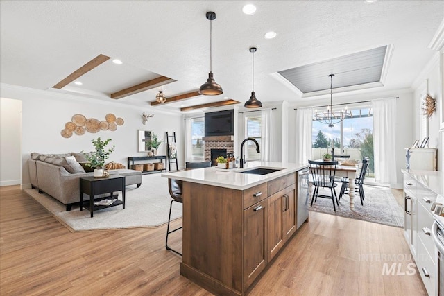 kitchen with light wood-style flooring, open floor plan, light countertops, a kitchen bar, and a fireplace