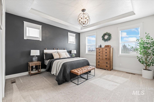 bedroom featuring a textured ceiling, light carpet, visible vents, baseboards, and a raised ceiling