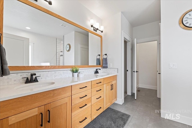 full bath featuring double vanity, baseboards, visible vents, and a sink