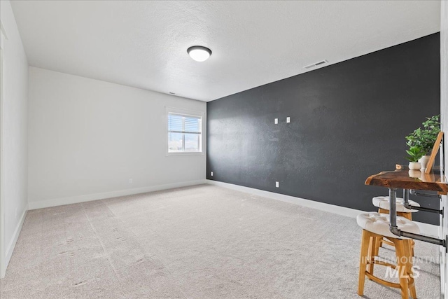 carpeted empty room featuring visible vents, a textured ceiling, and baseboards