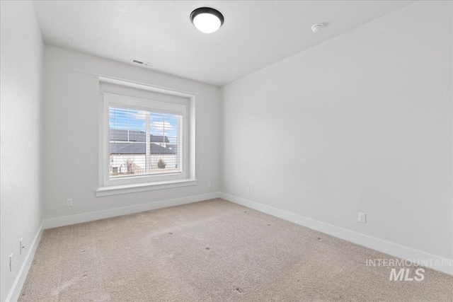 empty room featuring carpet flooring, visible vents, and baseboards