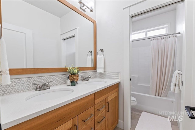 full bath featuring double vanity, toilet, backsplash, and a sink