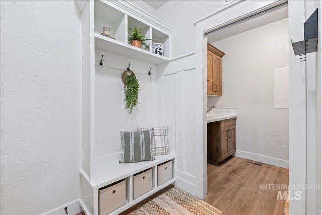 mudroom featuring visible vents, light wood-style flooring, and baseboards