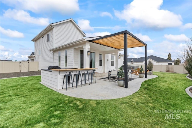 back of house featuring outdoor dry bar, a patio area, a yard, and a fenced backyard