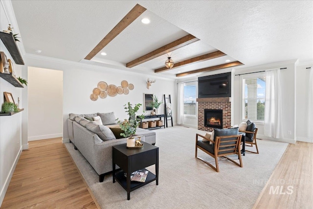 living area featuring beam ceiling, baseboards, a textured ceiling, and light wood finished floors