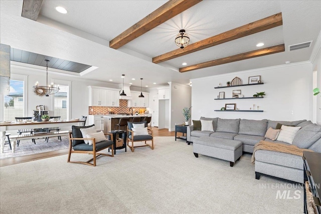 living room with visible vents, light wood-style flooring, ornamental molding, beamed ceiling, and a chandelier