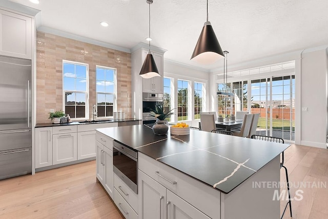 811 N Creekwater Lot 13/6, Eagle, ID 83616 - kitchen featuring built in appliances, a sink, healthy amount of natural light, light wood-style floors, and crown molding