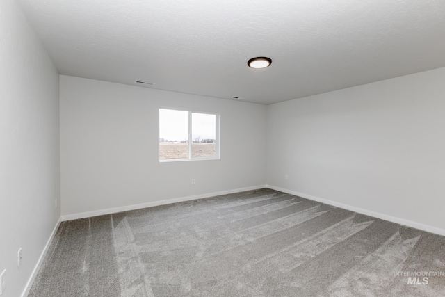 carpeted empty room with baseboards, visible vents, and a textured ceiling